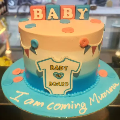 A sweet 'Baby on Board' cake for a baby shower. This design features a blue and peach ombre effect, cute button details, and a message from the baby to the mom-to-be.