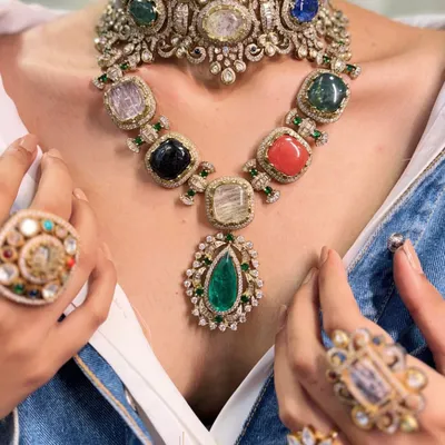 More is more when it comes to creating a moment. This look features a Navratna-style choker layered with a matching gemstone necklace, surrounded by statement rings, for a truly maximalist and royal statement.