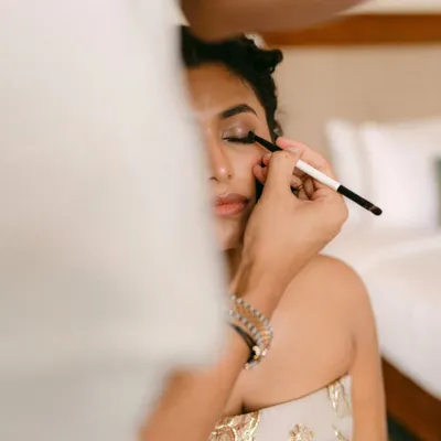 A close-up of a makeup artist applying eyeshadow to the bride. This shot captures the precision and artistry that goes into creating the perfect bridal look.