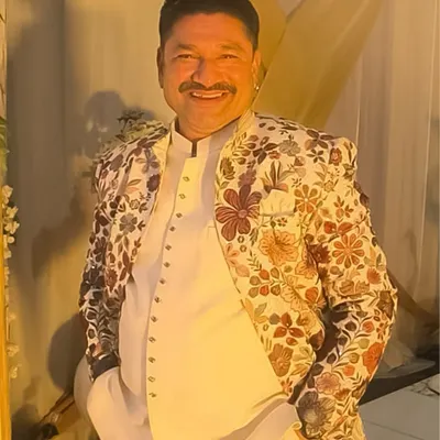 This client is wearing one of my unique floral embroidered jackets. It's a statement piece that pairs well with a simple white kurta, perfect for making a stylish impression at a wedding or festive gathering.