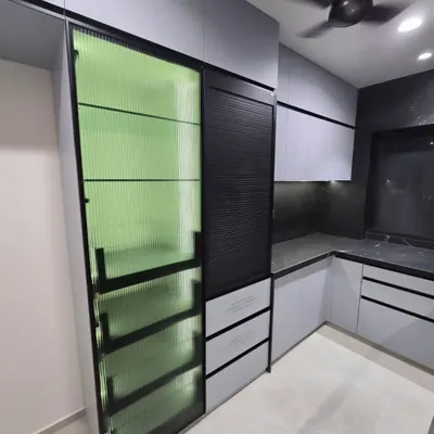 A close-up of our floor-to-ceiling pantry unit featuring a striking fluted green glass door. This detail adds texture, color, and a touch of retro elegance while partially obscuring the contents for a tidy look.
