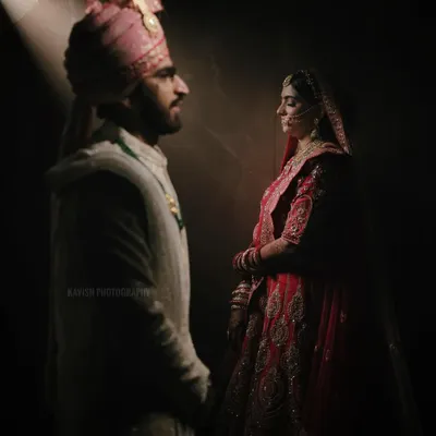 A powerful and artistic wedding portrait using a single spotlight to create a dramatic, cinematic feel. The image highlights the bride and groom's profiles as they face each other.