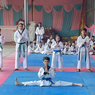 Flexibility is key to delivering high kicks. Here, one of our young students demonstrates a full split, showcasing the results of our dedicated stretching and conditioning routines.