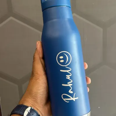 A simple and stylish personalized water bottle. This matte blue bottle is engraved with a name and a cute smiley face.