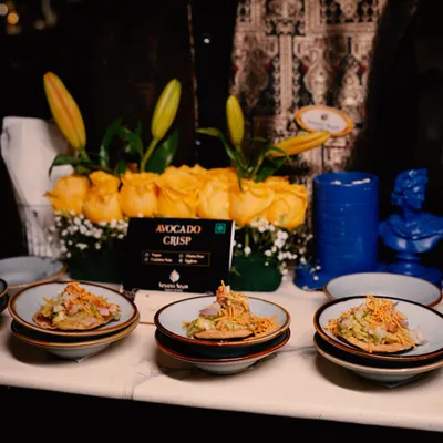 A server presents our signature Avocado Crisps. This dish is a perfect example of my fusion approach, combining creamy avocado with a crunchy base for a delightful bite-sized appetizer.