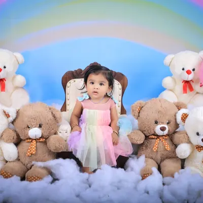 A dreamy rainbow and teddy bear picnic theme. This little girl in a pastel rainbow dress sits like a princess on her throne among the clouds and her furry friends.