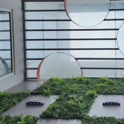 A view looking up from the courtyard in Dr. Harsha's home, showing the interplay of glass, greenery, and light.