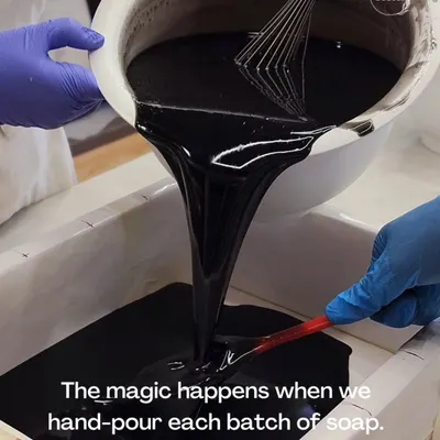 The process begins with the pour. Here, I'm hand-pouring a batch of rich, dark soap made with activated charcoal. This step is crucial for achieving a smooth, consistent texture in every single bar.