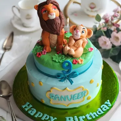 A majestic Lion King themed cake for a 9th birthday, featuring beautifully sculpted figures of Mufasa and Simba on a two-tier savanna backdrop.