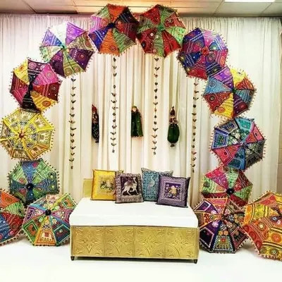 This beautiful backdrop features a full arch made from colorful Rajasthani umbrellas. It's a perfect photo booth or seating area for a Mehndi or Sangeet function.