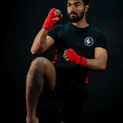 A fighter demonstrates a perfect knee strike, a fundamental and powerful weapon in Muay Thai and MMA. This studio shot highlights the form and balance required for effective striking.