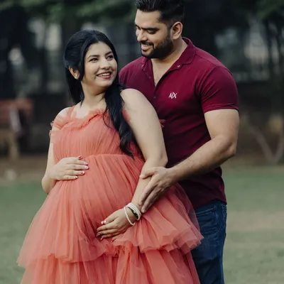 A beautiful maternity shoot moment. This couple looks so happy, and she is glowing in our peach-colored tiered tulle gown, which is a popular rental for photoshoots.