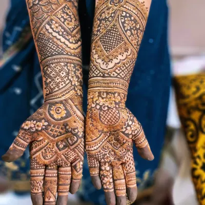 A Dubai-style full-hand mehendi with a mix of geometric patterns and floral elements. The design is dense and intricate, covering the hands completely for a rich look.