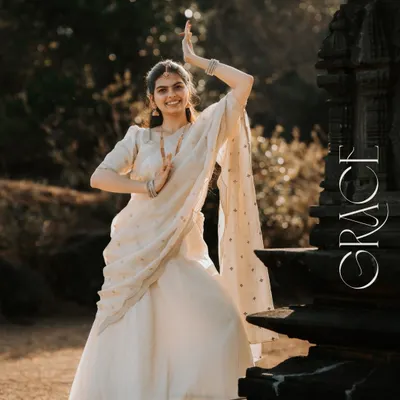 A portrait that captures the essence of grace. The bride-to-be's classical dance pose in a beautiful white lehenga against the backdrop of a traditional stone temple is pure poetry.