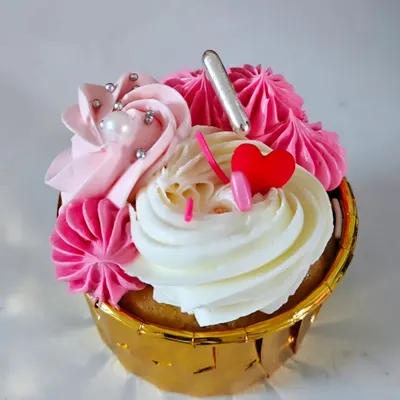 A close-up of my vanilla cupcake with two-toned strawberry and vanilla buttercream. It's decorated with silver sprinkles, a sugar pearl, and a little red heart for a lovely finish.