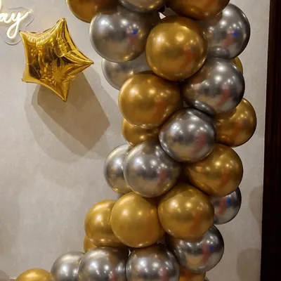 A close-up of a balloon arch showcasing the quality of our materials. The image highlights the reflective sheen of the chrome gold and silver balloons, accented with a gold star foil balloon for extra sparkle.