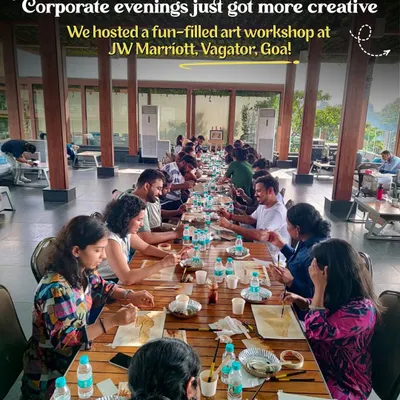A long table of corporate employees fully engaged in a coffee painting workshop at the JW Marriott in Goa, a perfect creative break for any team.