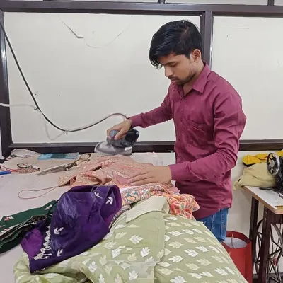 One of my skilled artisans carefully ironing a garment. This final press is a crucial step to ensure the outfit has a flawless, crisp finish before delivery.