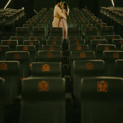 A wide shot of the couple embracing in an empty movie theatre. This unique pre-wedding shoot location turns their love story into its own feature film.