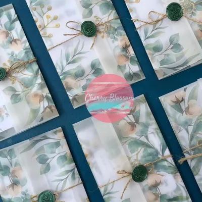 Elegant and rustic 'Save The Date' cards. These invitations feature a translucent floral vellum wrap, tied with jute string and finished with a custom green wax seal for a personalized, handcrafted feel.