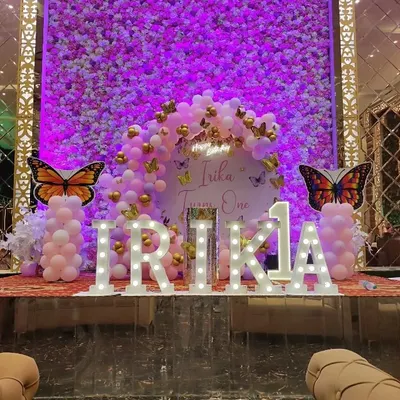 A grand butterfly-themed first birthday with a purple flower wall backdrop, large marquee letters, and butterfly cutouts.