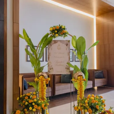A warm and traditional welcome for guests. This entrance decor features bright yellow marigolds, lush banana leaves, and a personalized welcome sign, creating a festive and inviting atmosphere.