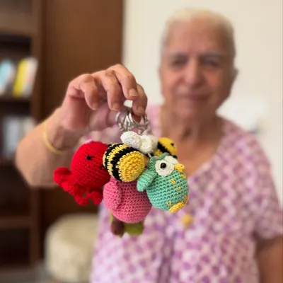 Dadi holding a handful of our cutest keychain charms. From bees to octopuses and owls, these little companions are sure to make you smile.