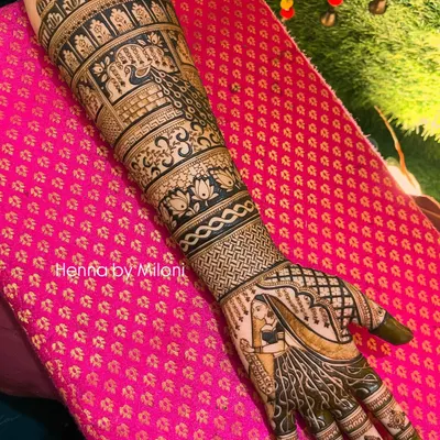 A full-arm bridal mehendi design showcasing a beautiful bride figure. The entire arm is covered in layers of traditional patterns, including peacocks, lotuses, and intricate jaal work, creating a truly magnificent look.