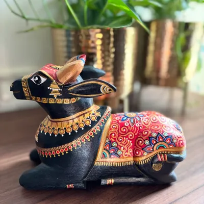 A seated Nandi sculpture exuding a calm, majestic aura. The classic combination of black, red, and gold detailing makes this a truly timeless piece of decor, perfect for adding a touch of spiritual elegance to your space.