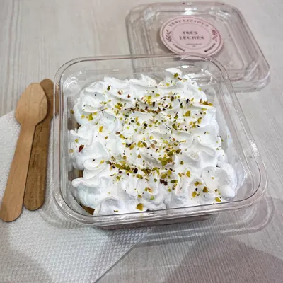 Our famous Tres Leches, now available in an eggless version. This photo shows our light, airy sponge soaked in three kinds of milk, topped with whipped cream and a sprinkle of pistachios, packaged and ready for you to enjoy.