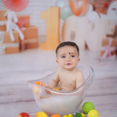 A wider view of the fruity milk bath session, showing the complete setup with a blurred background that keeps the focus on the happy baby.