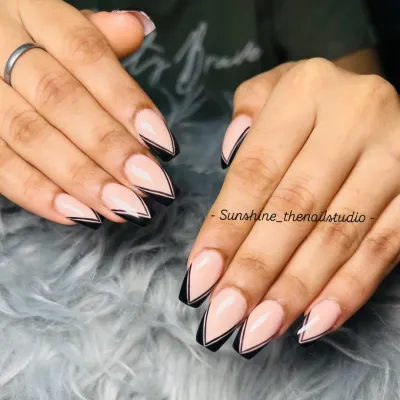 A sharp and modern take on the French manicure. This design features a double line V-shape French tip in black on long, coffin-shaped nails.
