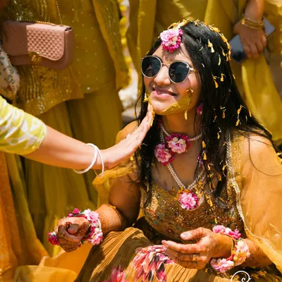A cool bride enjoying her Haldi ceremony. The mix of traditional turmeric paste and modern sunglasses perfectly captures her personality.