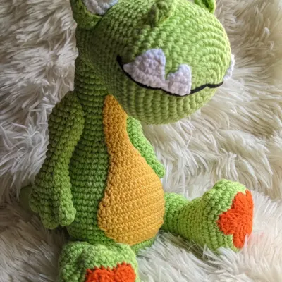 A big, friendly green dinosaur with a yellow belly and a wide grin. He's a soft and cuddly friend for any dino lover.