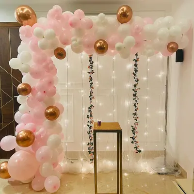 This elegant corner arch is made with soft pink, white, and rose gold balloons. It frames a delicate fairy light curtain, creating a beautiful and sophisticated backdrop for cake cutting or taking photos at your event.
