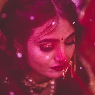 A close-up candid shot of the bride during the ceremony, capturing the emotion of the moment. The deep red tones and soft focus are part of my signature moody and artistic wedding photography style.