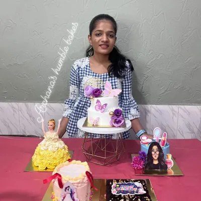 A happy student showcasing the variety of cakes made in a single workshop, including a doll cake, a tiered butterfly cake, and a photo print cake.