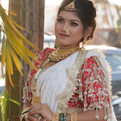 A stunning Maharashtrian bride in a white saree with a contrasting red blouse. The look is completed with a traditional nath and gold jewellery, creating a perfect blend of modern elegance and timeless tradition.