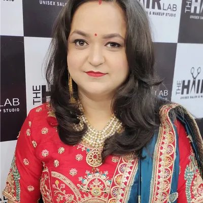 A happy client looking absolutely radiant after her hair styling session. Her hair is perfectly coiffed with soft waves that complement her festive look.
