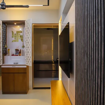 A beautifully crafted mandir with intricate jali-cut doors, integrated lighting, and storage. It is positioned thoughtfully within the living area, creating a serene spiritual corner.