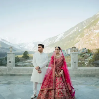 A portrait that speaks volumes. The couple stands against the breathtaking expanse of the Manali mountains, their regal wedding attire contrasting beautifully with the raw nature. This is the essence of a destination wedding.