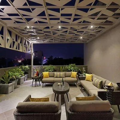 A modern terrace designed for evening entertainment. This space features a custom geometric-patterned pergola with integrated lighting, comfortable lounge seating, and large planters to create a sophisticated city-view retreat.