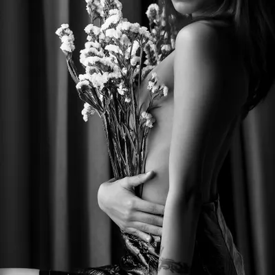 An artistic and intimate black and white portrait. Using a bouquet to create shape and shadow, this image is a perfect example of fine art boudoir photography, focusing on sensuality and mystery.