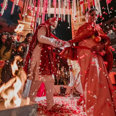 The sacred pheras around the holy fire. This shot, with the shower of red petals, feels like it's straight from a Sanjay Leela Bhansali film, full of tradition and grandeur.