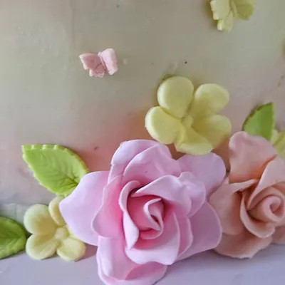 A close-up of the handcrafted sugar flowers from the enchanted garden cake. I shape and dust each petal by hand to create realistic and delicate blooms, like these pink roses and yellow blossoms.