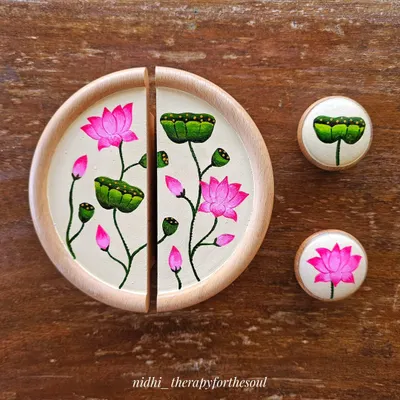 The complete set of hand-painted handles for a TV unit. The large circular handle is split into two, and I also painted two smaller matching knobs with a single lotus and a lotus pod.