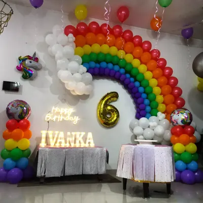 A bright and cheerful rainbow themed birthday party. This setup includes a large rainbow balloon arch, rainbow balloon pillars, a 'Happy Birthday' neon sign, and a unicorn foil balloon for extra magic.