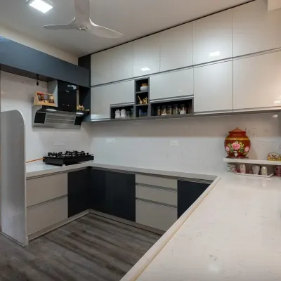 This U-shaped modular kitchen uses a dual-tone scheme of dark grey and off-white to create a sophisticated look. The layout provides ample counter space and an efficient work triangle, making it ideal for busy households.