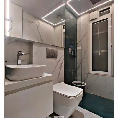 This compact bathroom feels spacious and bright thanks to floor-to-ceiling marble-look tiles and a floating vanity. The rectangular LED light fixture above the mirror provides excellent, even illumination.
