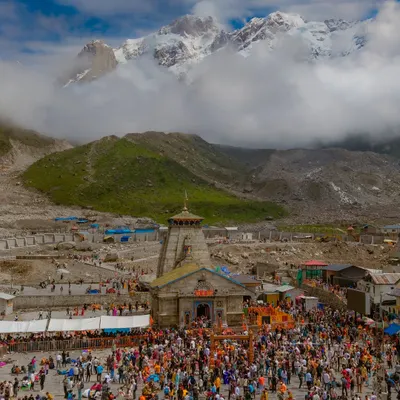 The sacred Kedarnath Temple in Uttarakhand, with the majestic snow-capped Himalayas as its backdrop. The crowd of pilgrims shows the immense faith this place inspires.